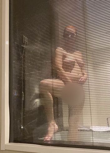 Pregnant redhead woman in the hotel bathroom with window, looking through